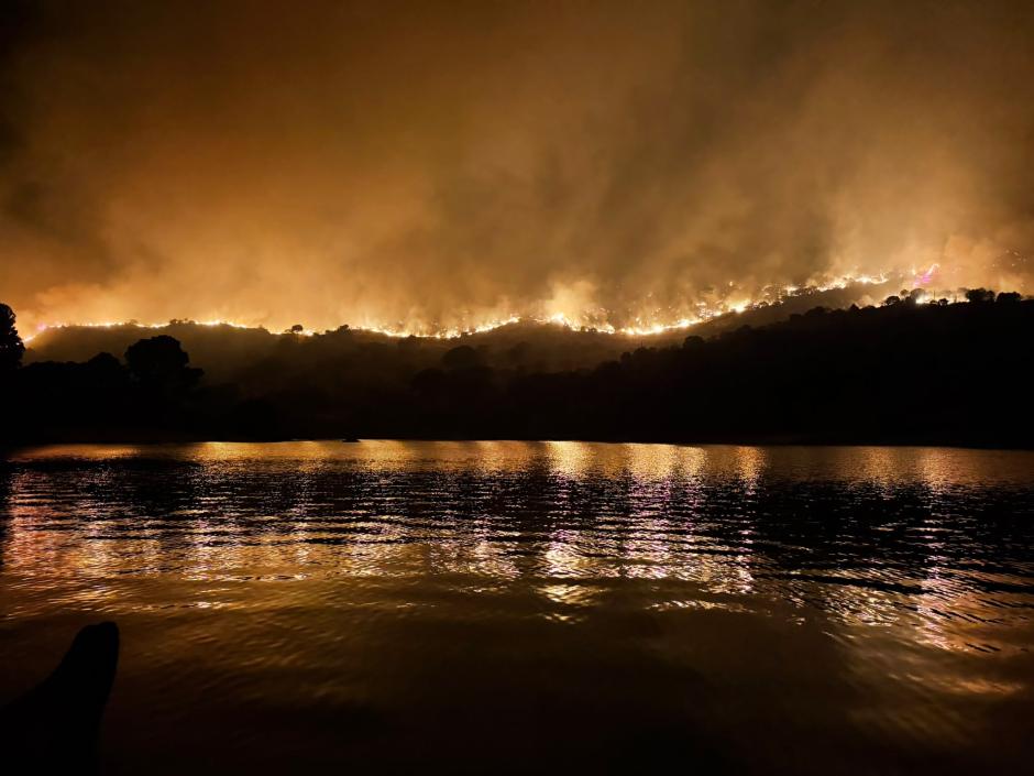 Impresionante imagen del pantano de San Juan rodeado por las llamas