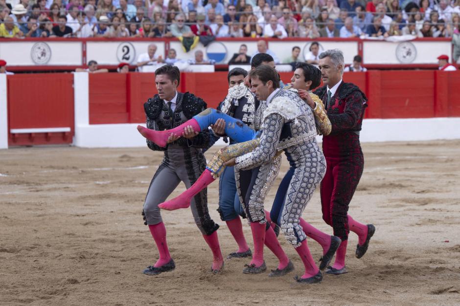 El diestro Marco Pérez ayudado por su cuadrilla tras sufrir una cogida en su faena durante la corrida de toros celebrada este sábado en la Feria de Santiago de Santander.