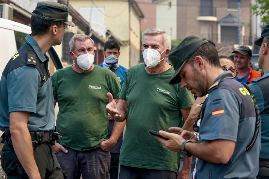 Vecinos de Casavieja protegidos con mascarillas conversan con agentes de la Guardia Civil