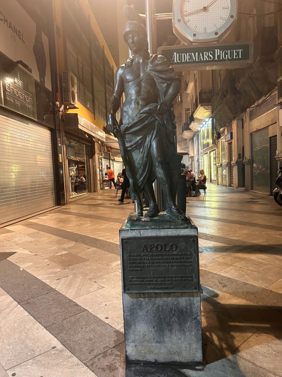 El dios Apolo, patrón del Oráculo de Delfos, conocido como la deidad de la luz, franquea la calle donde se ubica el establecimiento