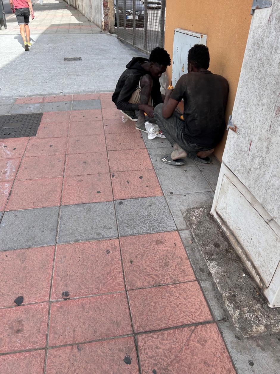 Dos subsaharianos improvisan un picnic en plena calle tras conseguir alimentos en un supermercado de la Avenida de España