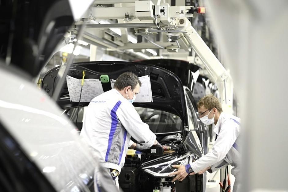 Dos operarios de Volkswagen instalan un faro en un modelo ID.3 en la planta de Zwickau, Alemania.