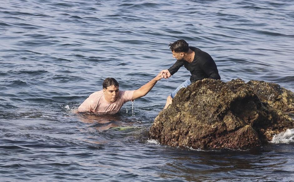 Un marroquí ayudando a otro a salir del agua para ingresar en Ceuta