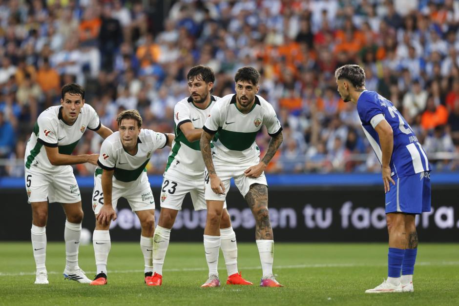 Los jugadores del Elche (i) esperan el centro durante el partido