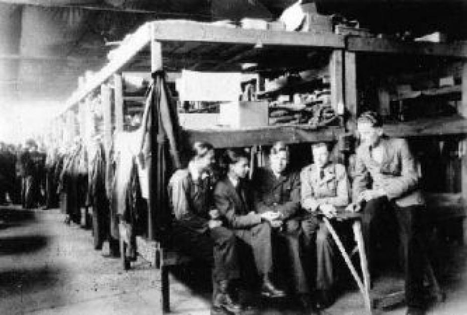 interior de un barracón con literas de madera y prisioneros reunidos en el Séminaire des Barbelés (el seminario de alambre de espino), un campo especial para prisioneros de guerra alemanes que eran seminaristas o sacerdotes católicos tras la Segunda Guerre Muncial
