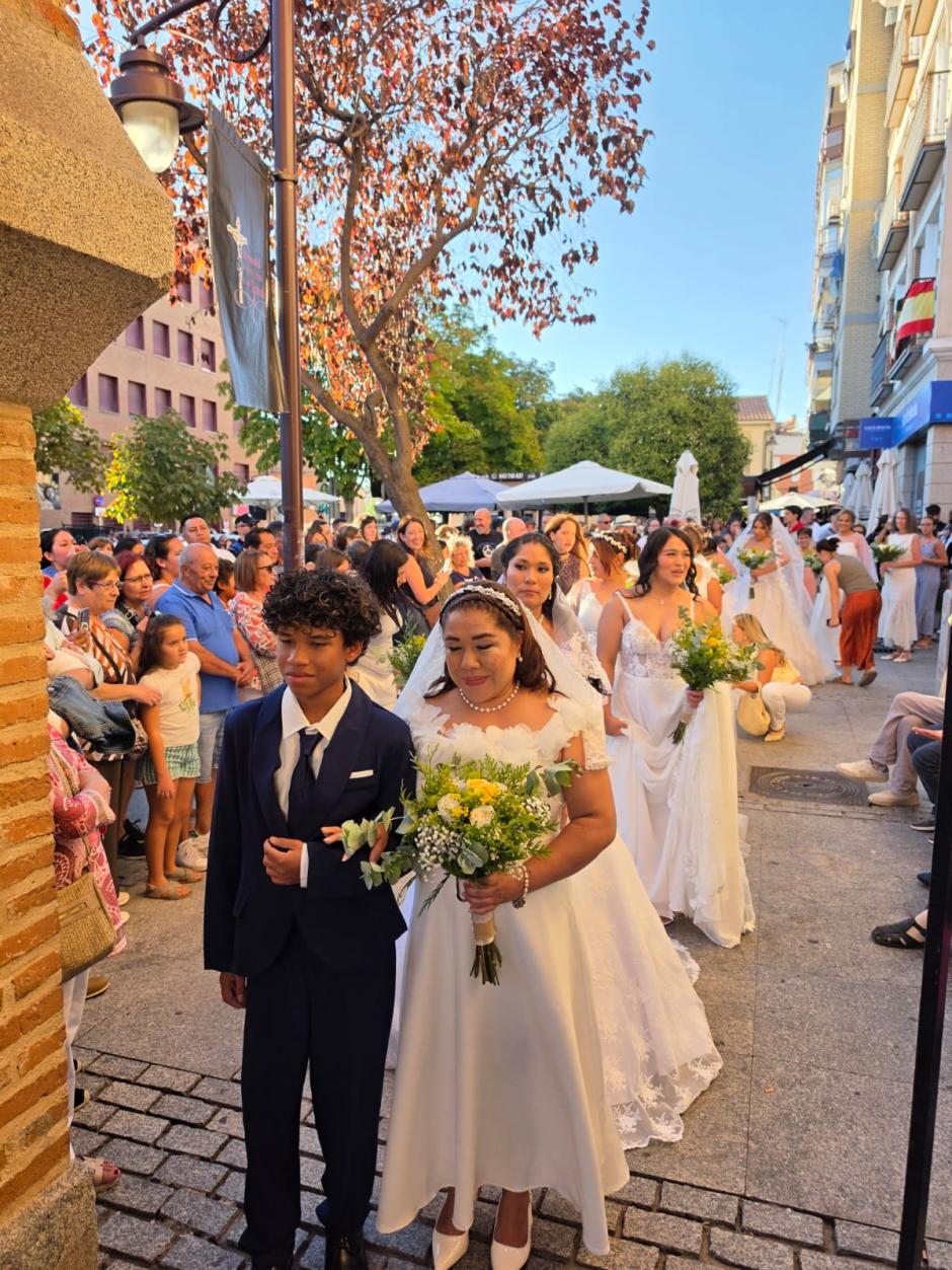 Una de las novias entra al templo del brazo de su hijo