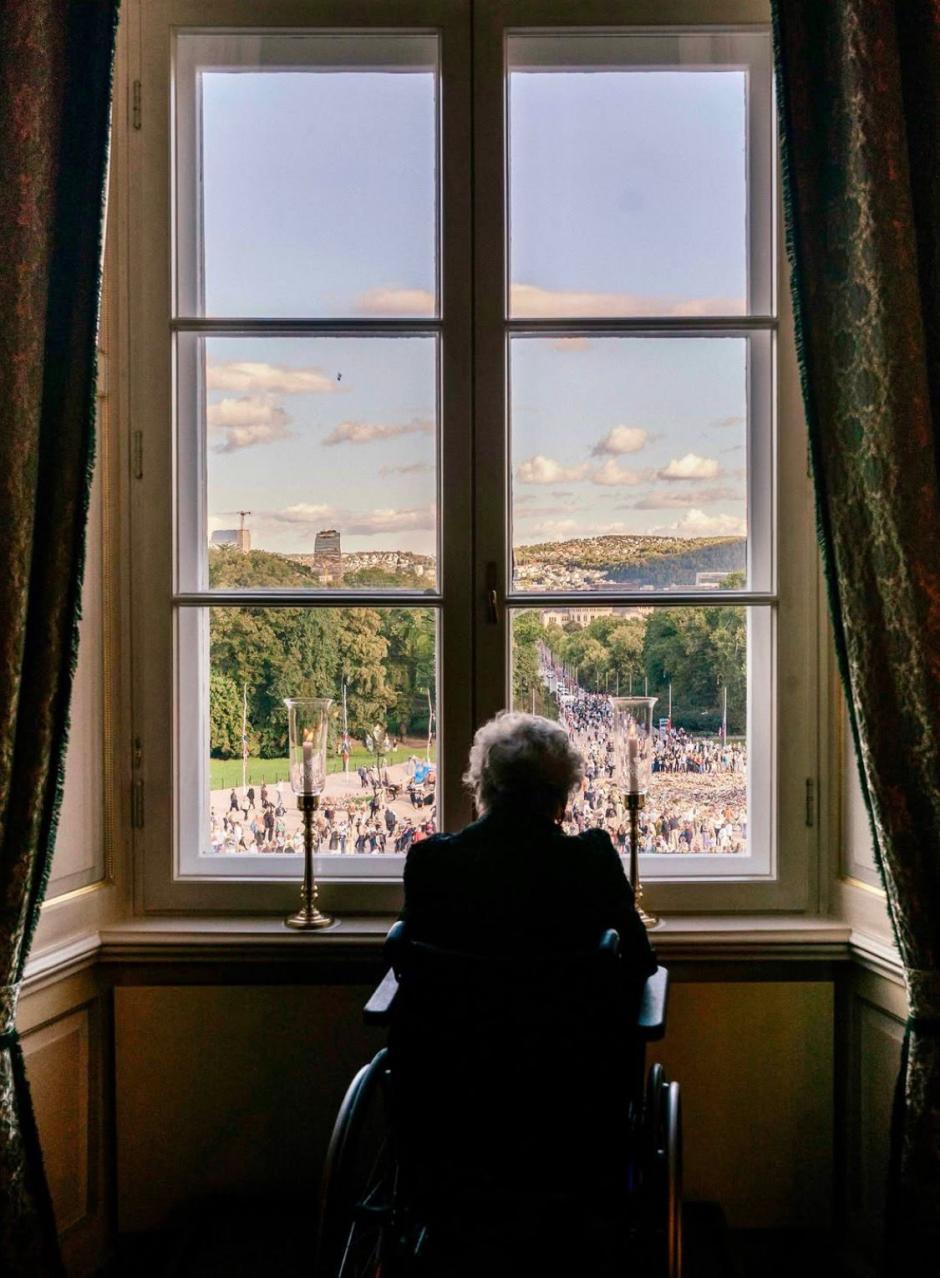 La Princesa Astrid de Noruega observa desde su silla de ruedas lo que ocurre a través de la ventana del palacio