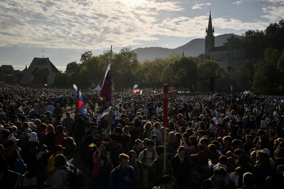Los fieles llegan a la pradera del Santuario de Nuestra Señora de Lourdes, con la Basílica de la Inmaculada Concepción al fondo