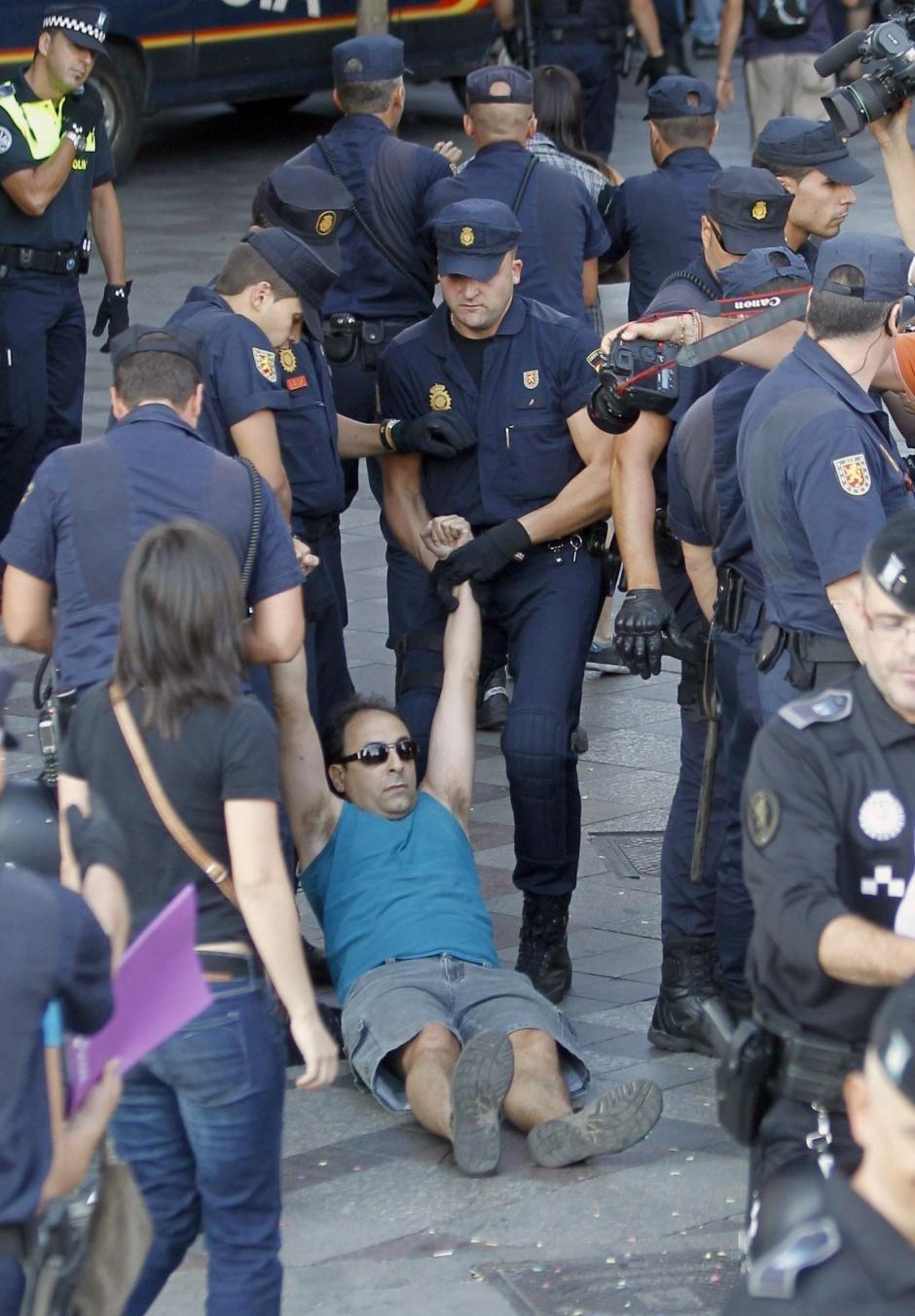 Varios policías nacionales desalojan a un indignado, esta tarde, de la madrileña Puerta del Sol, a 2 de agosto de 2011