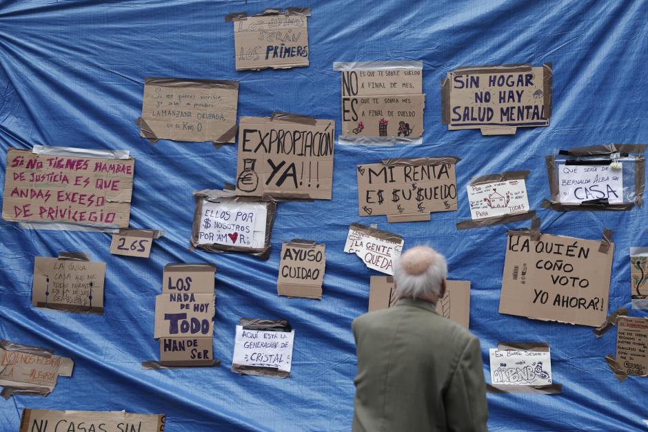 Un hombre observa los carteles instalados en la Puerta del Sol de Madrid este domingo