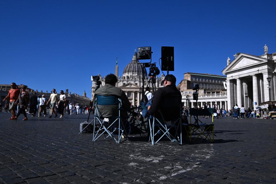 Dos hombres se sientan detrás de una cámara y de las luces para la retransmisión en directo en la plaza de San Pedro