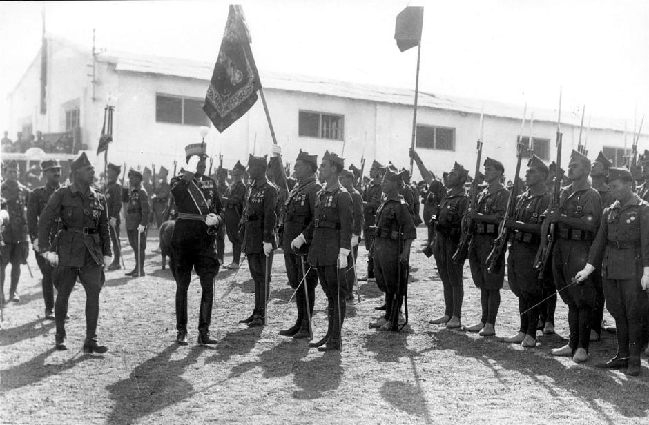 Alfonso XIII, acompañado por el coronel Eugenio Sanz de Larín, jefe del Tercio, pasa revista a las fuerzas legionarias en la ceremonia de entrega de la primera bandera a esta unidad