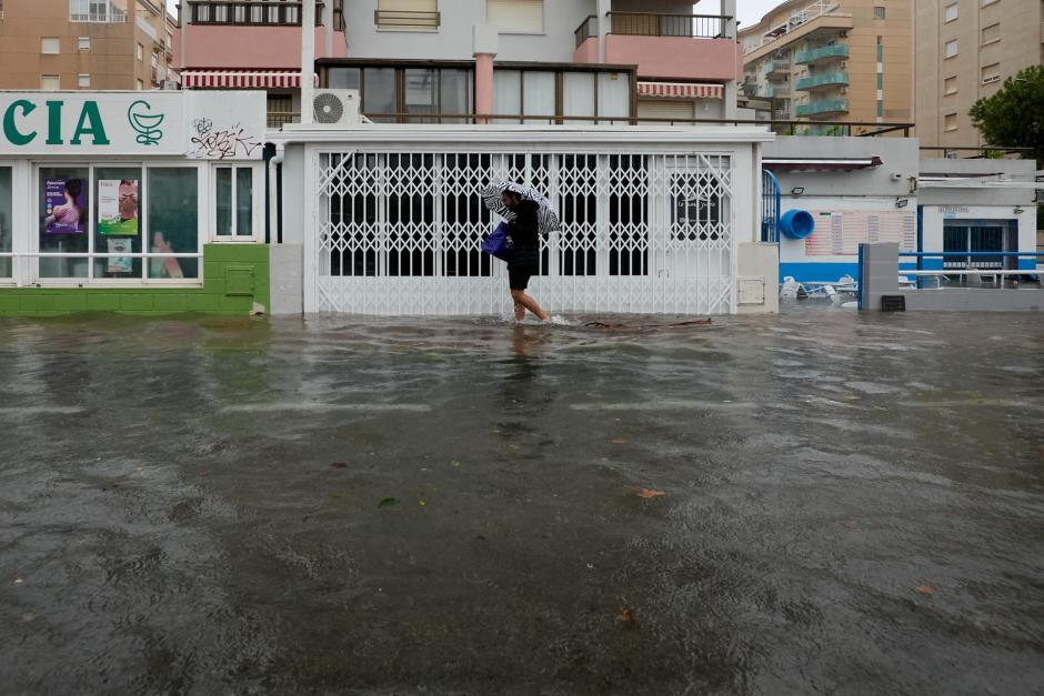 BELLREGUARD (VALENCIA), 19/10/2026.- Un policía local se acerca a dos personas que abandonan la zona de la playa de Bellreguard (Valencia) a través de una calzada inundada este lunes. Cruz Roja ha preparado un albergue provisional en Gandía (Valencia) para personas afectadas por las fuertes lluvias provocadas por la dana Adam y su equipo de avituallamiento atiende a personas que circulan por carreteras y han sido evacuadas hacia el área de servicio de La Safor. EFE/Manuel Bruque