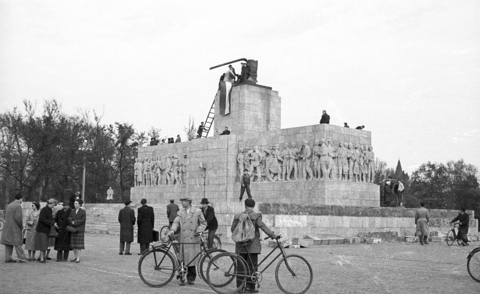 Manifestantes anticomunistas y nacionalistas colocan una bandera nacional húngara sobre los restos de una estatua demolida de Stalin