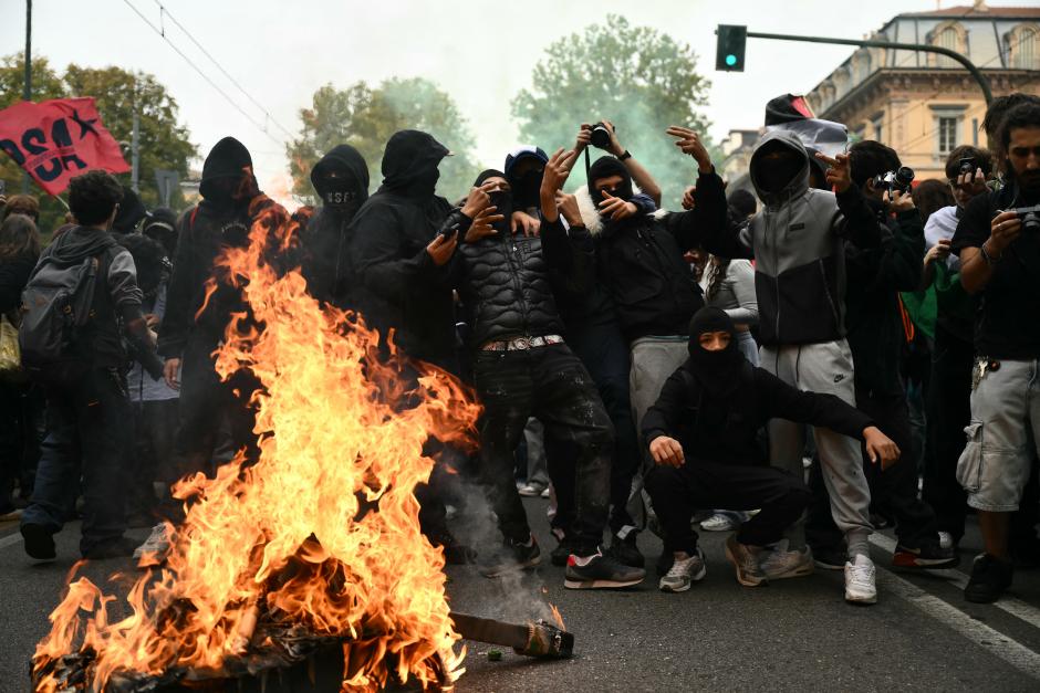 Manifestantes encapuchados frente a una hoguera en una calle de Turín, Italia