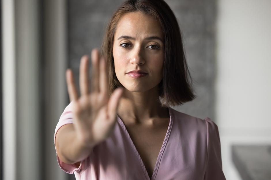 Saying no. Head shot portrait serious determined young woman look at camera hold palm forward in stop prohibition gesture. Personal boundaries defense empowered refusal harassment resistance concept